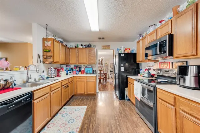 a kitchen with stainless steel appliances a stove top oven a sink dishwasher and a refrigerator