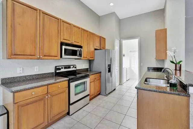 a kitchen with granite countertop a stove top oven microwave and refrigerator