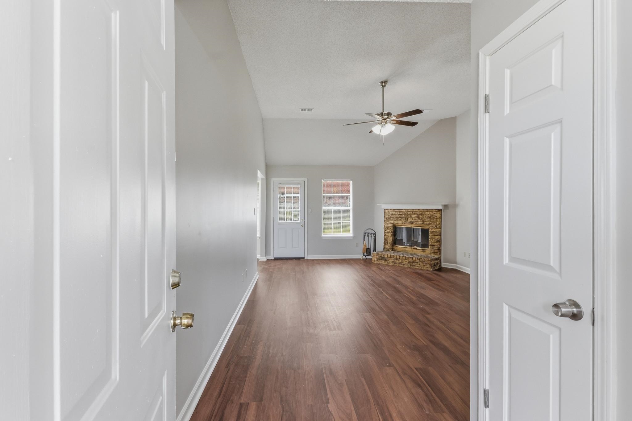 4101 Long Creek Road Memphis, TN 38125 - Photo 28 of 36 Bright living area featuring wood-finish flooring, a vaulted ceiling with a ceiling fan, and a stone-faced fireplace with a mantel