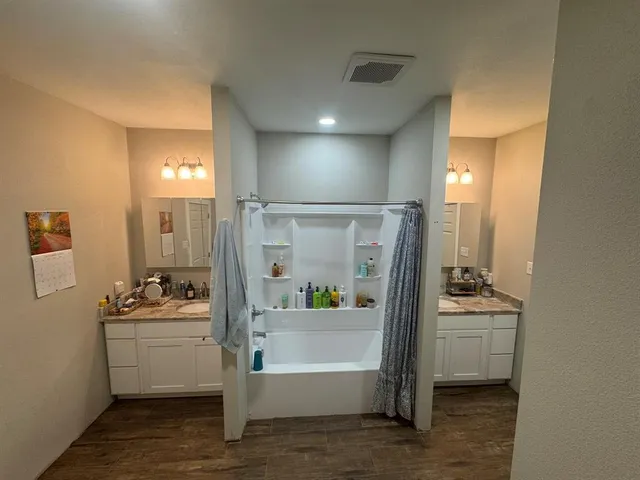 a bathroom with a tub sink a mirror and a shower