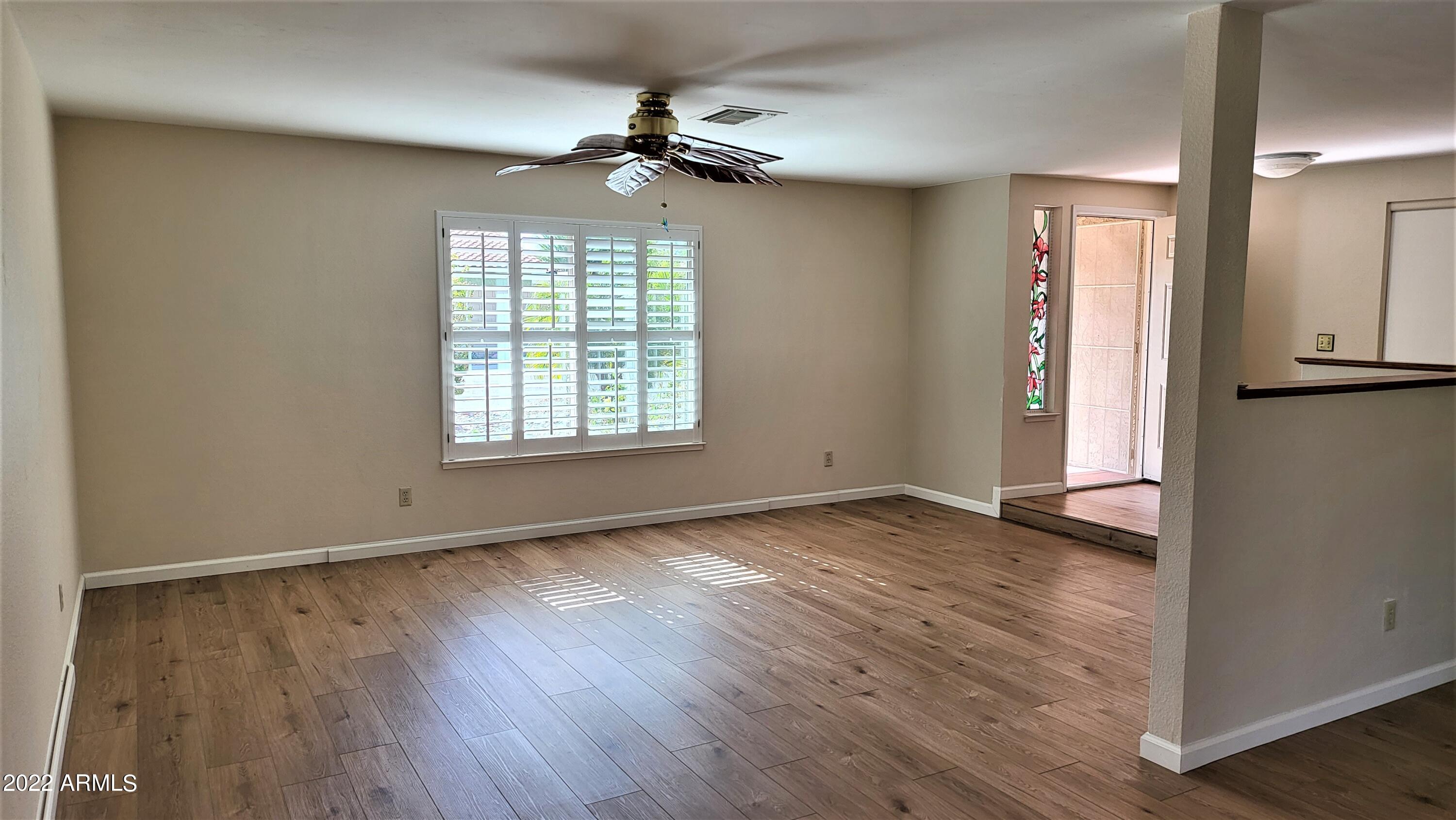 1940 East Hearn Road Phoenix, AZ 85022 - Photo 13 of 51 an empty room with wooden floor fan and windows
