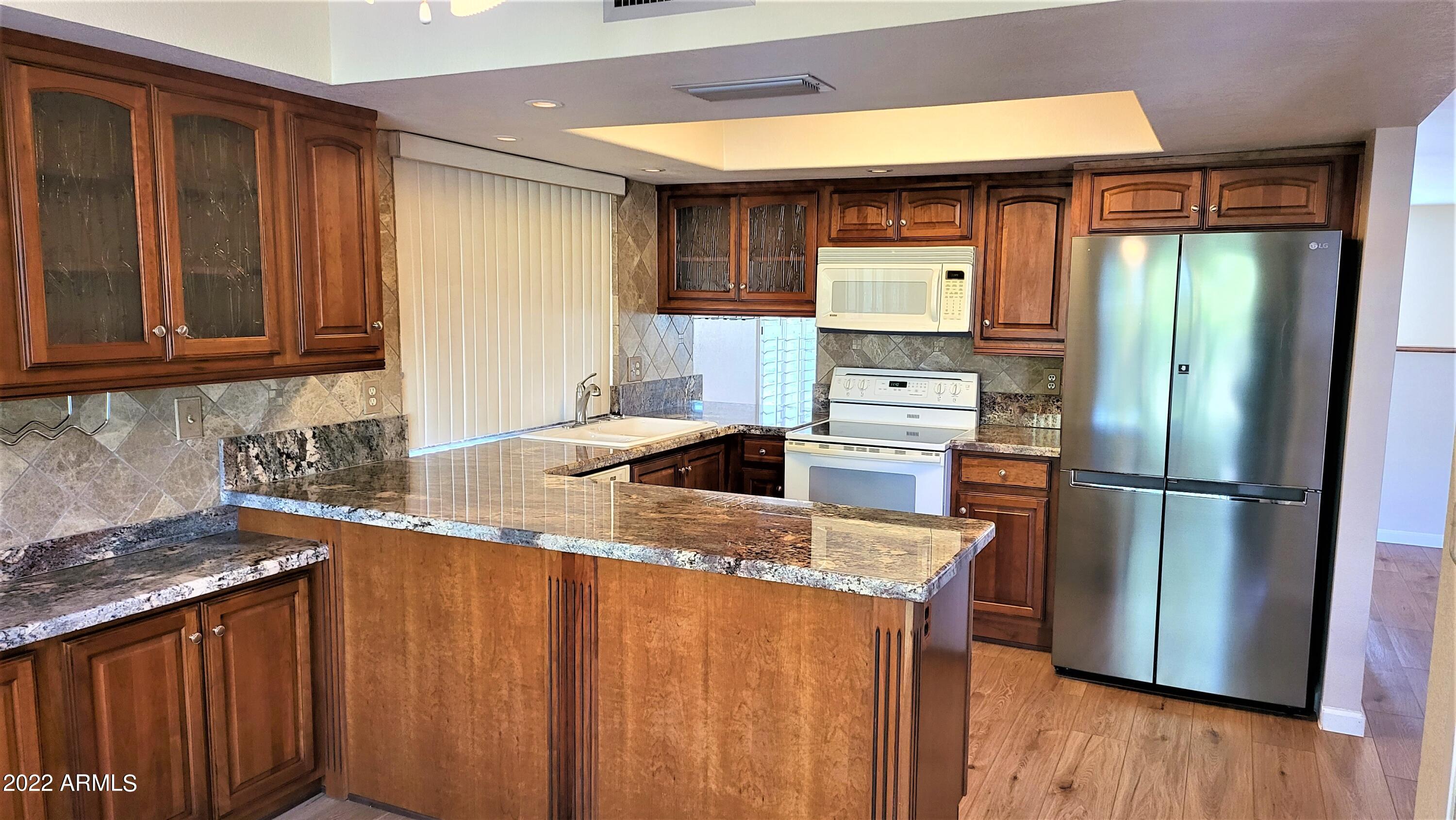 1940 East Hearn Road Phoenix, AZ 85022 - Photo 19 of 51 a kitchen with stainless steel appliances granite countertop a refrigerator a stove a sink dishwasher and wooden cabinets with a large window