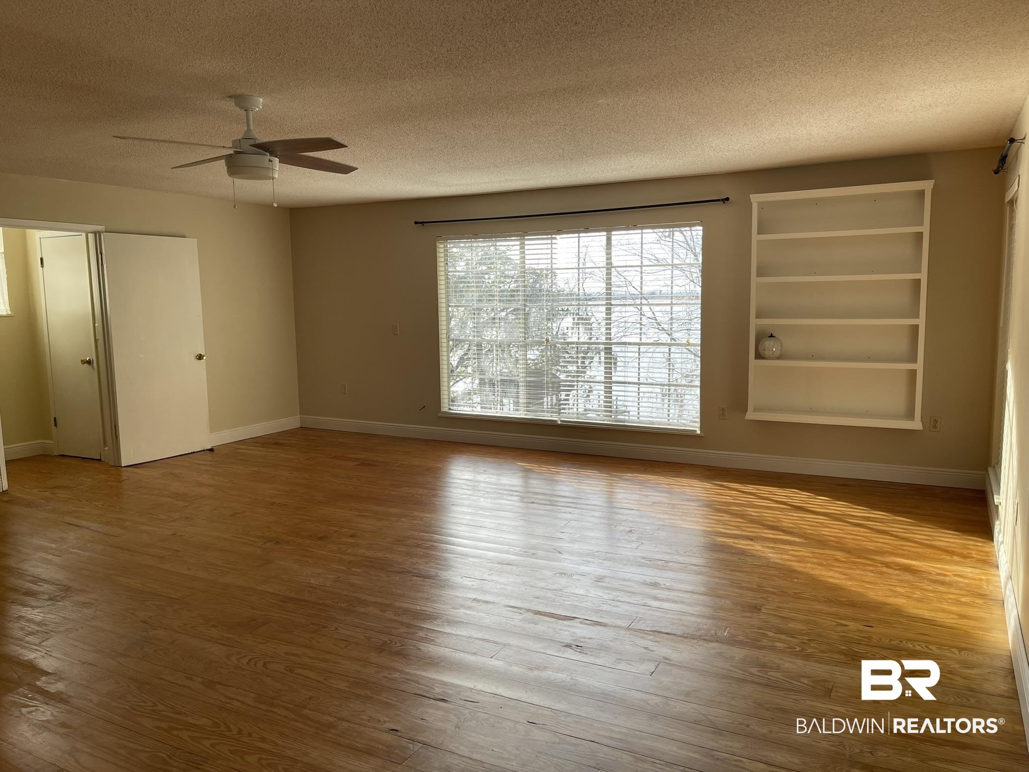 6621 Purvis Road Daphne, AL 36527 - Photo 36 of 59 Unfurnished room featuring a textured ceiling, hardwood / wood-style flooring, built in shelves, and ceiling fan