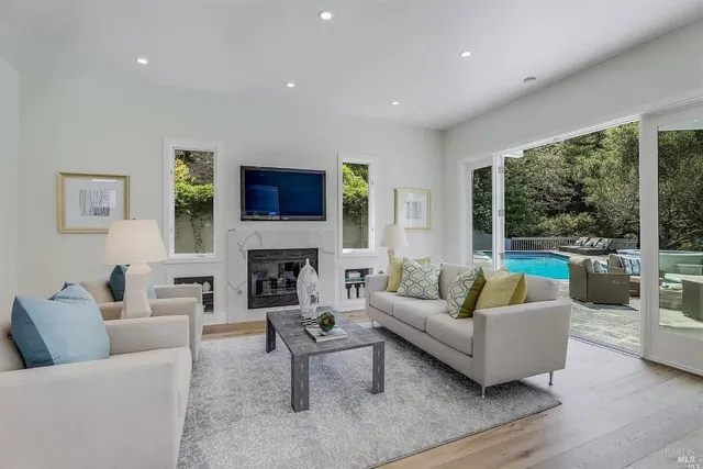 a living room with furniture a fireplace a flat screen tv and a large window