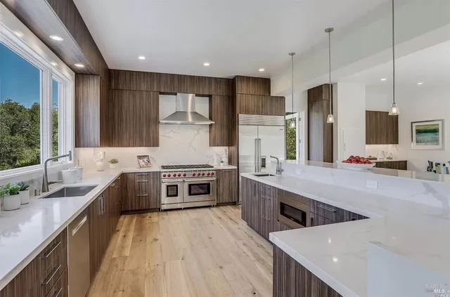 a large kitchen with stainless steel appliances lots of counter space wooden floor and window