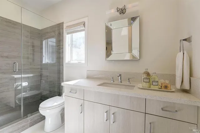 a bathroom with a toilet sink vanity and mirror
