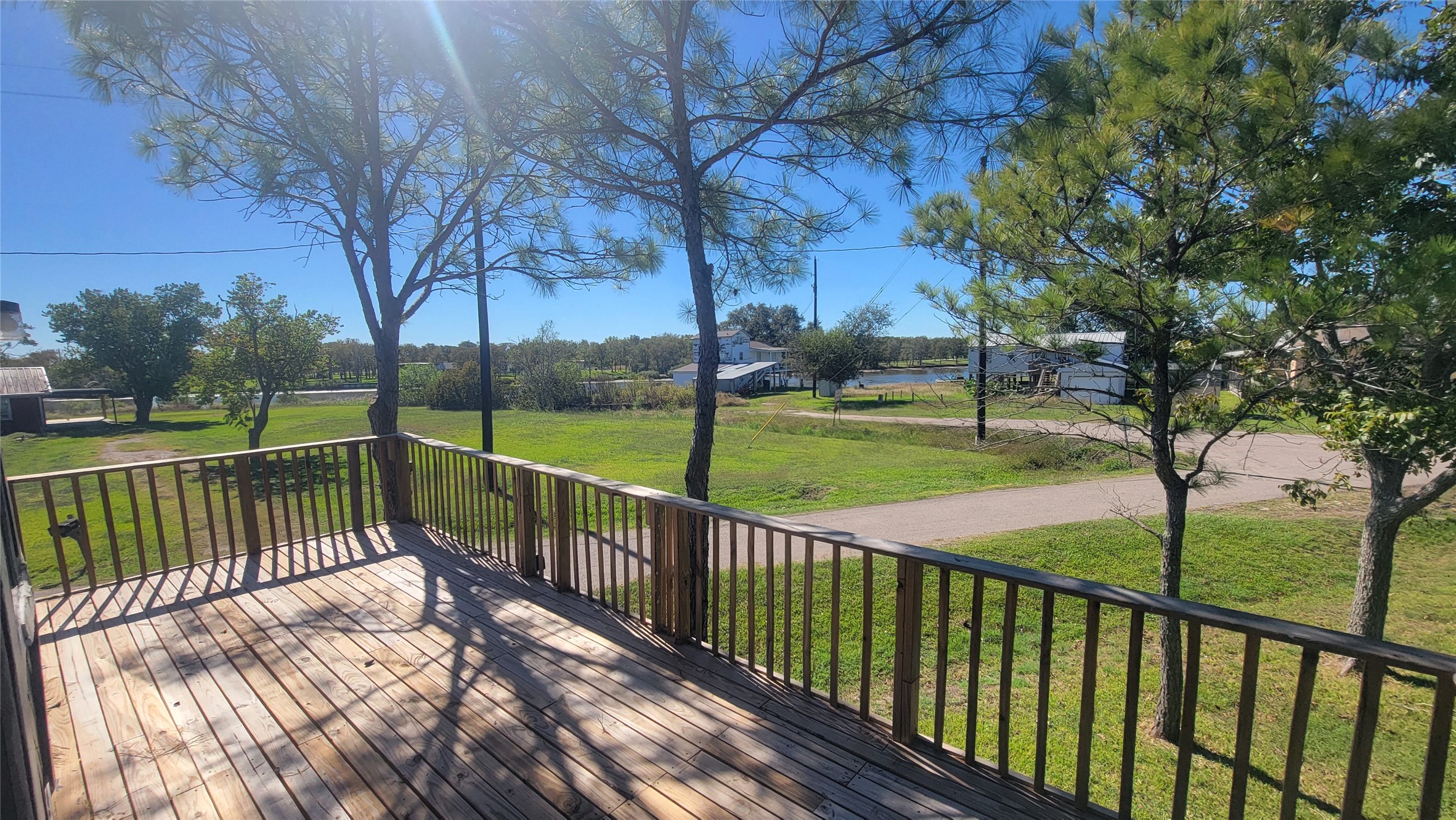 12018 Sandpiper Road Angleton, TX 77515 - Photo 8 of 48 This photo showcases a spacious wooden deck overlooking a lush green yard with mature trees, offering a serene and private outdoor space with a countryside view.