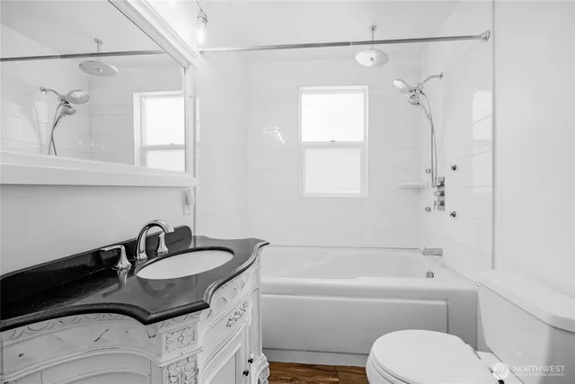 a bathroom with a granite countertop sink a toilet and shower