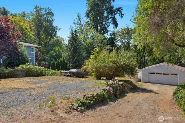 a backyard of a house with large trees and plants