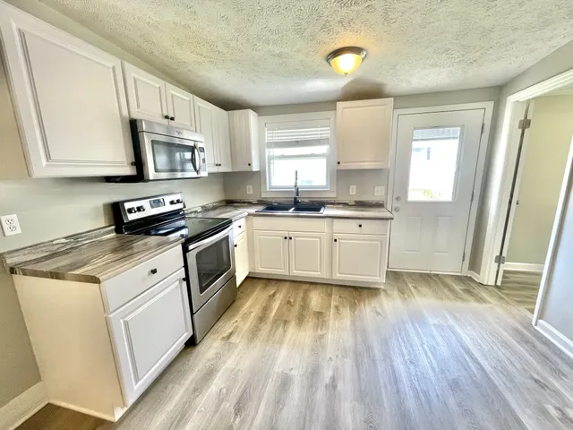 a kitchen with granite countertop a sink cabinets and wooden floor