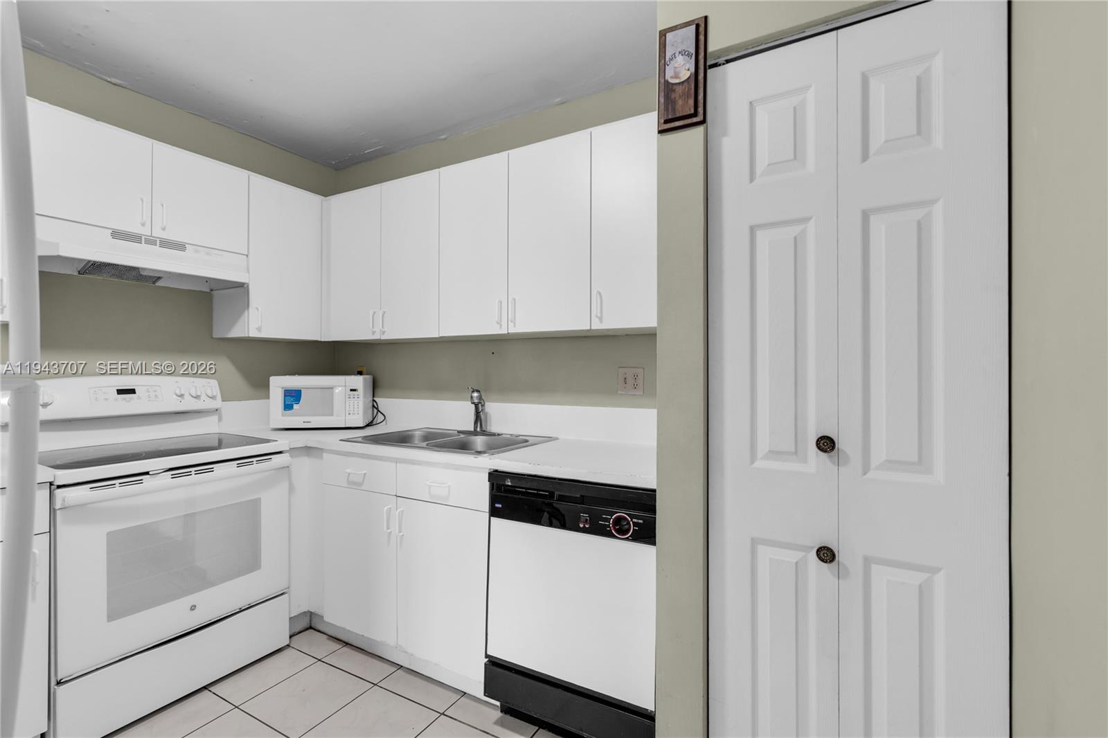 8050 Northwest 8th Street, Unit 305 Miami, FL 33126 - Photo 4 of 25 a kitchen with white cabinets and white appliances