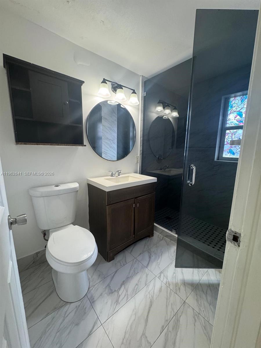 6941 Bay Drive, Unit A1 Miami Beach, FL 33141 - Photo 7 of 10 a bathroom with a toilet a sink and mirror