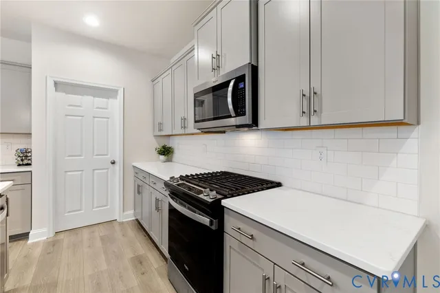 a kitchen with stainless steel appliances white cabinets and a stove top oven