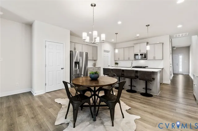 a view of a dining room and livingroom with furniture wooden floor a chandelier