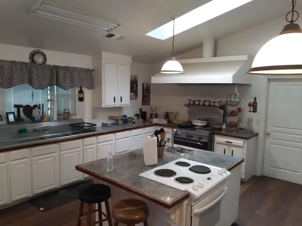 a kitchen with stainless steel appliances a stove a sink cabinets and wooden floor