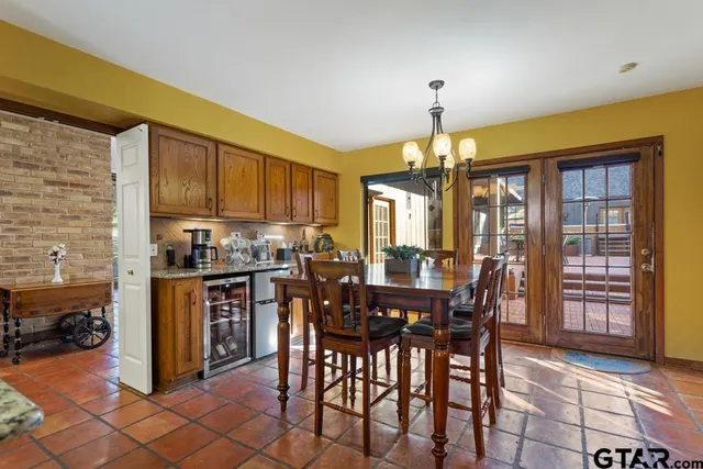 a dining room with stainless steel appliances granite countertop a dining table chairs and a refrigerator