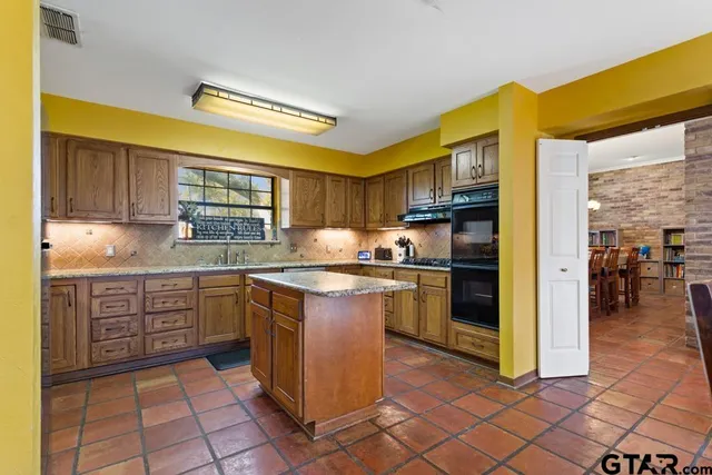 a kitchen with stainless steel appliances granite countertop a stove a sink and a refrigerator