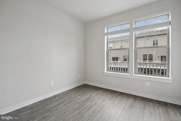 a view of an empty room with wooden floor and windows
