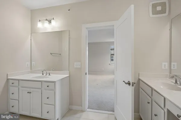 a bathroom with a granite countertop sink two mirror and shower
