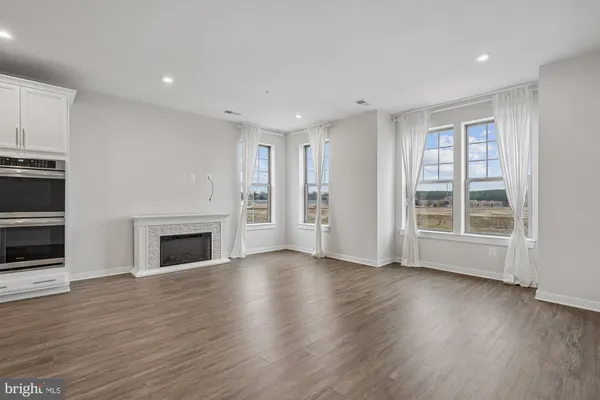 a view of an empty room with wooden floor fireplace and a window