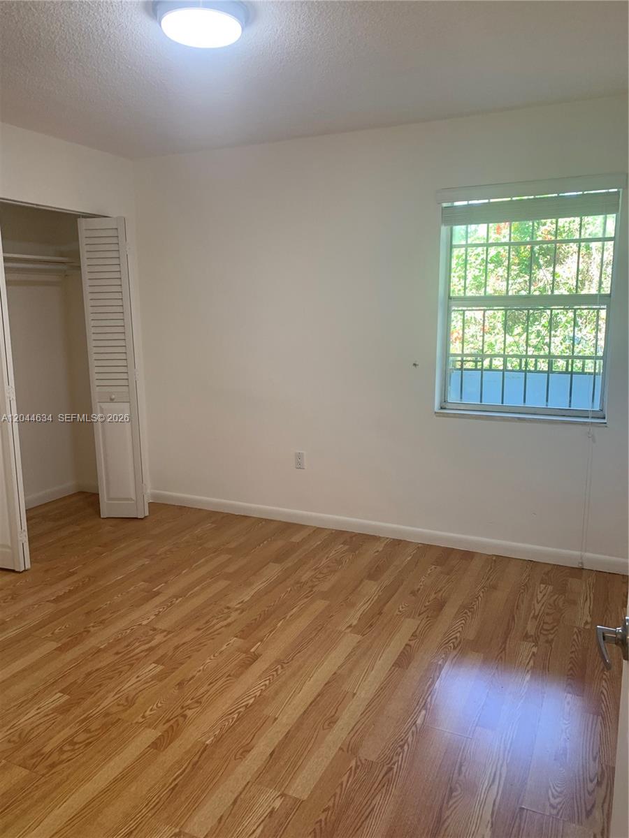 2460 Southwest 18th Avenue, Unit 1205 Miami, FL 33133 - Photo 13 of 21 a view of an empty room with wooden floor and a window