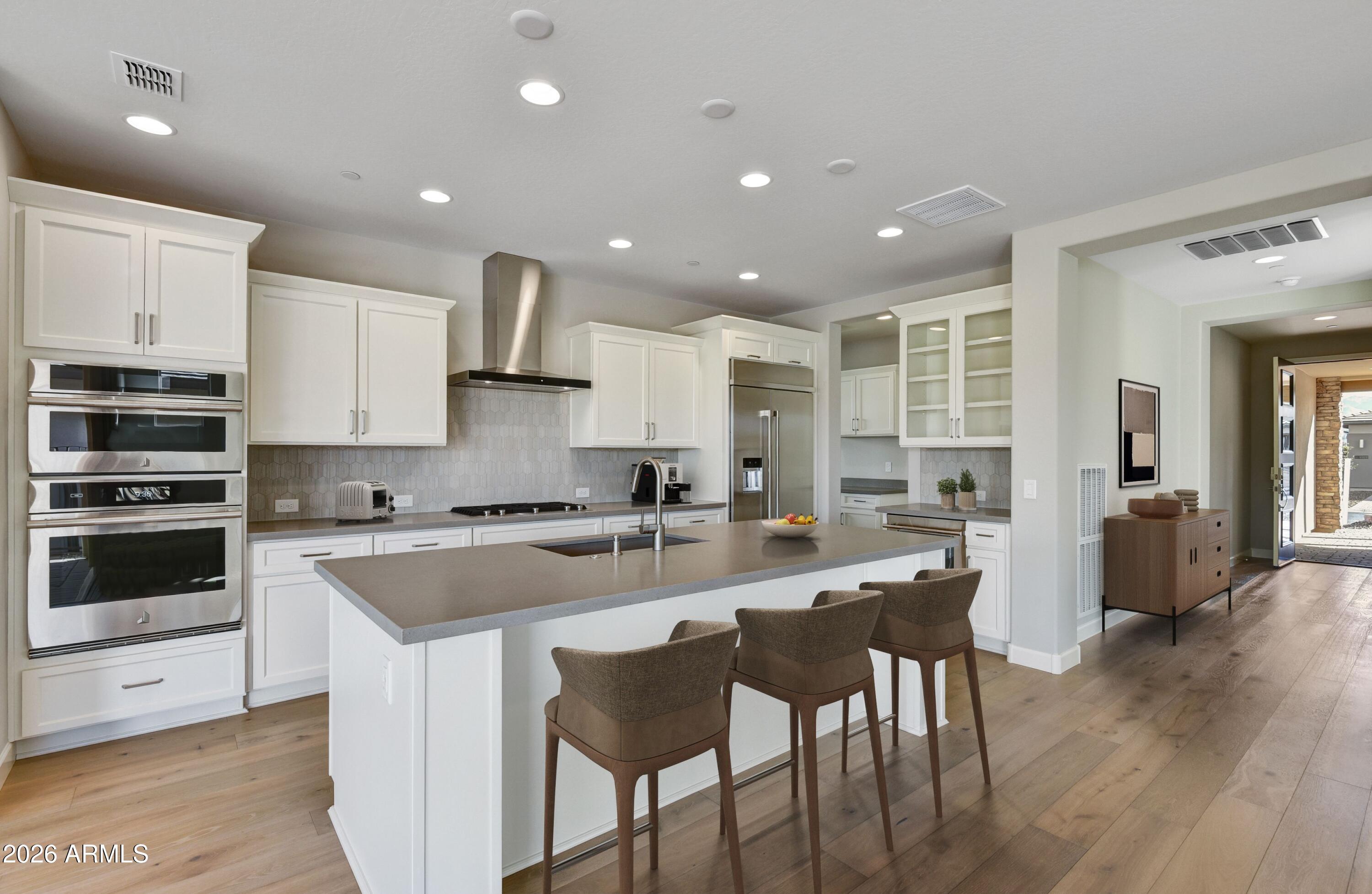 28702 North Camel Rock Court Rio Verde, AZ 85263 - Photo 6 of 38 a kitchen with stainless steel appliances kitchen island granite countertop a stove a sink a refrigerator and white cabinets with wooden floor