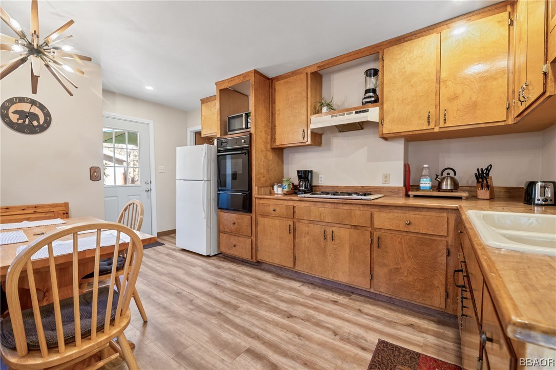 456 Riverside Avenue Sugarloaf, CA 92386 - Photo 4 of 19 a kitchen with stainless steel appliances granite countertop a refrigerator a stove a sink dishwasher and wooden cabinets with wooden floor