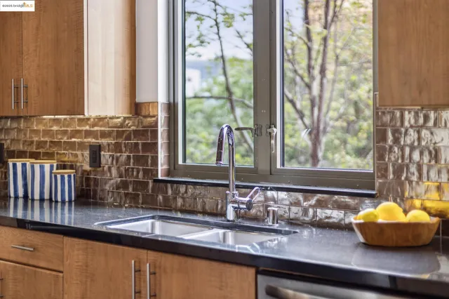 a kitchen with granite countertop stainless steel appliances a sink window and cabinets