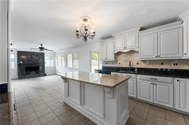 a kitchen with kitchen island granite countertop a sink a stove and cabinets