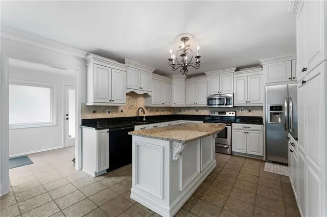 a kitchen with kitchen island granite countertop a sink cabinets and stainless steel appliances