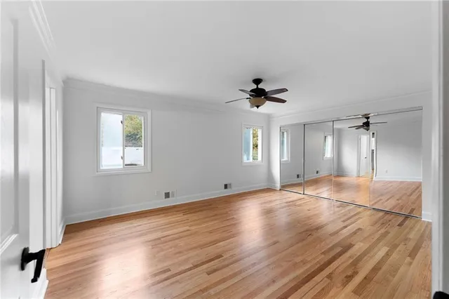 a view of empty room with wooden floor and fan