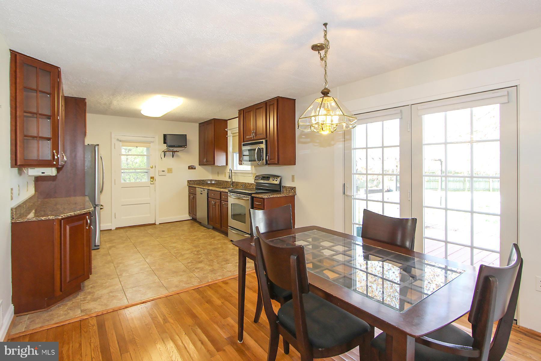 20820 Slidell Road Boyds, MD 20841 - Photo 11 of 29 a kitchen with stainless steel appliances granite countertop a stove top oven a refrigerator a sink dishwasher a dining table and chairs with wooden floor