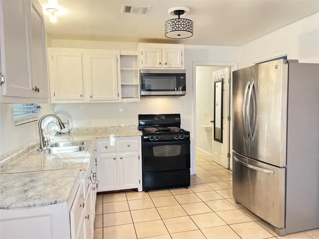 a kitchen with a refrigerator sink and white cabinets