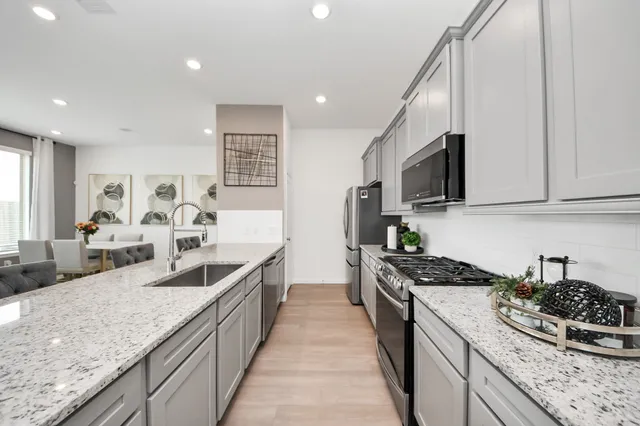 a large kitchen with stainless steel appliances granite countertop a lot of counter space and wooden floors