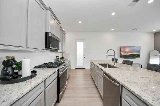 a large kitchen with stainless steel appliances granite countertop a sink a stove and a wooden cabinets