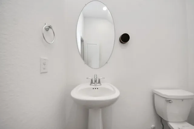 a bathroom with a sink a toilet and a mirror