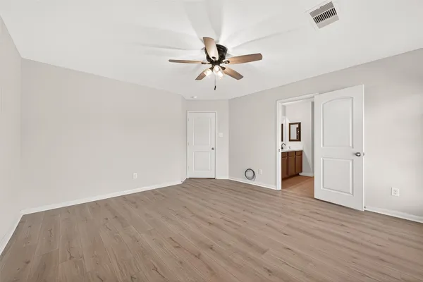 an empty room with wooden floor ceiling fan and windows