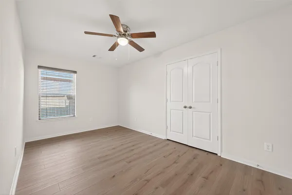 an empty room with wooden floor closet and windows
