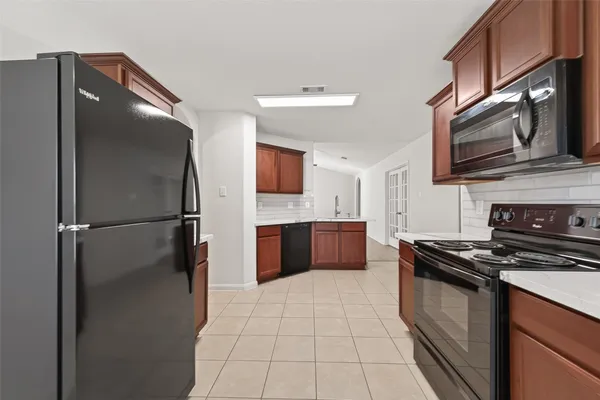a kitchen with stainless steel appliances granite countertop a refrigerator a stove a sink and a microwave