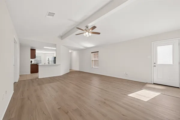 an empty room with wooden floor and a ceiling fan