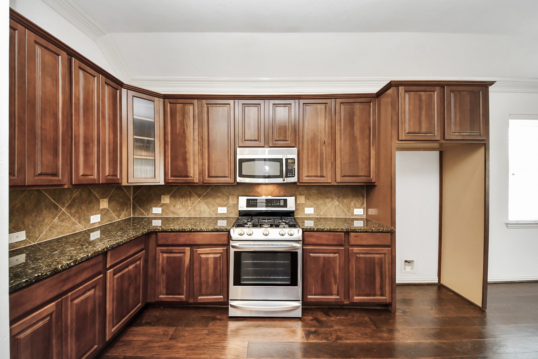 2907 Bright Sky Court Spring, TX 77386 - Photo 11 of 27 a kitchen with granite countertop wooden cabinets stainless steel appliances and a window