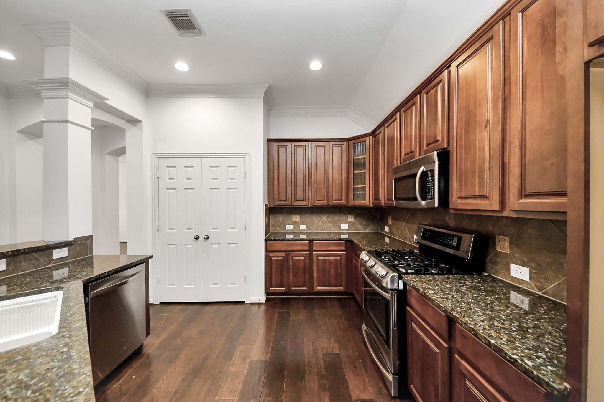 2907 Bright Sky Court Spring, TX 77386 - Photo 9 of 27 a kitchen with stainless steel appliances granite countertop a stove top oven a sink dishwasher and a refrigerator with wooden floor