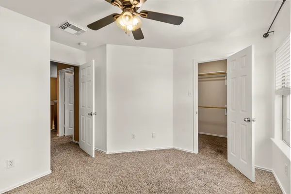 an empty room with a window and a fan