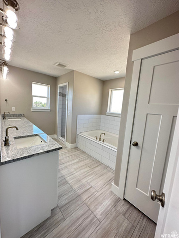 1171 West 2330 North Helper, UT 84526 - Photo 14 of 26 Full bath featuring double vanity, a garden tub, a textured ceiling, and a stall shower