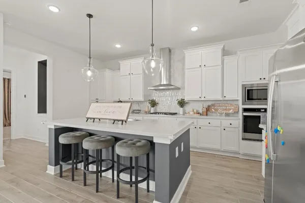 a kitchen with stainless steel appliances kitchen island granite countertop a sink a stove a refrigerator and island with wooden floor