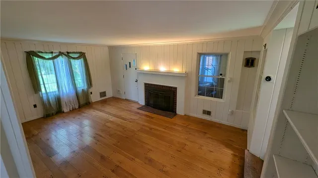 a view of empty room with wooden floor and fireplace