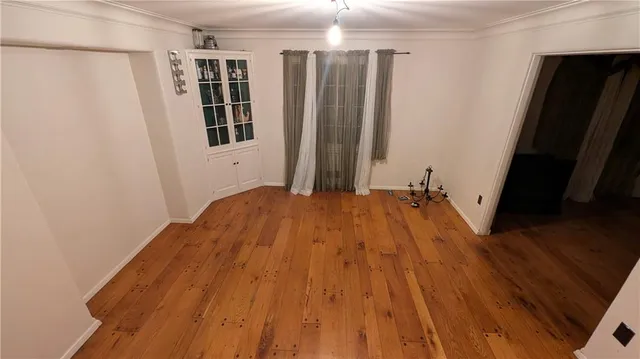 a view of a bedroom with wooden floor and a window
