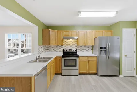 a kitchen with stainless steel appliances granite countertop a refrigerator a stove top oven and sink
