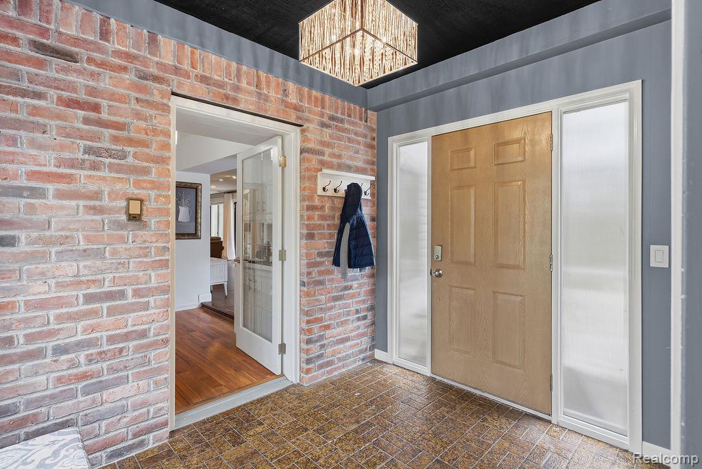 11111 Hibner Road Hartland, MI 48353 - Photo 12 of 59 Foyer entrance with brick wall, brick patterned floors, and hanging lights