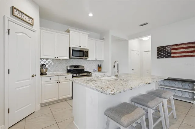 a kitchen with granite countertop a sink stove and white cabinets